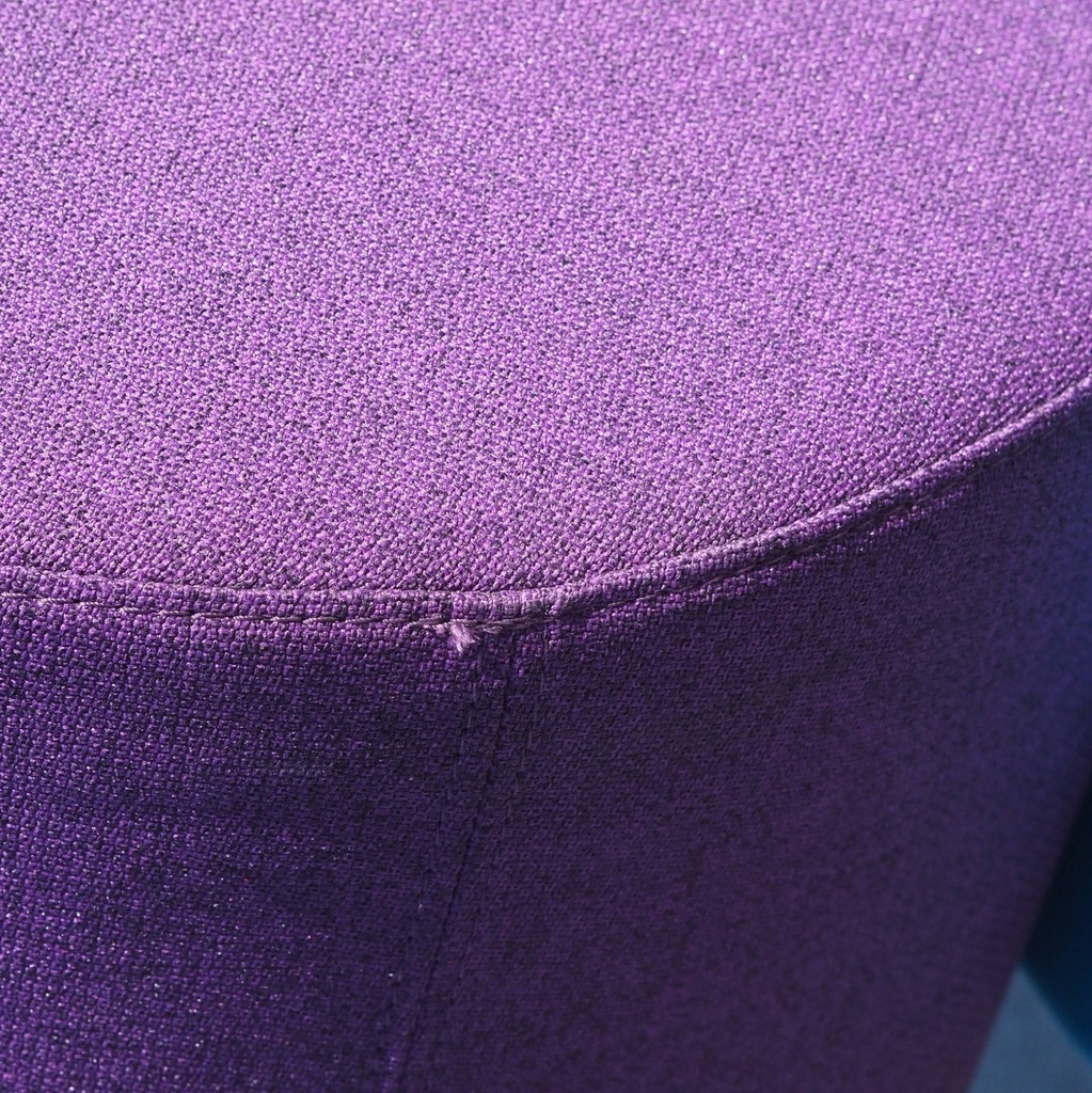 Round ottoman upholstered in various colorful fabric