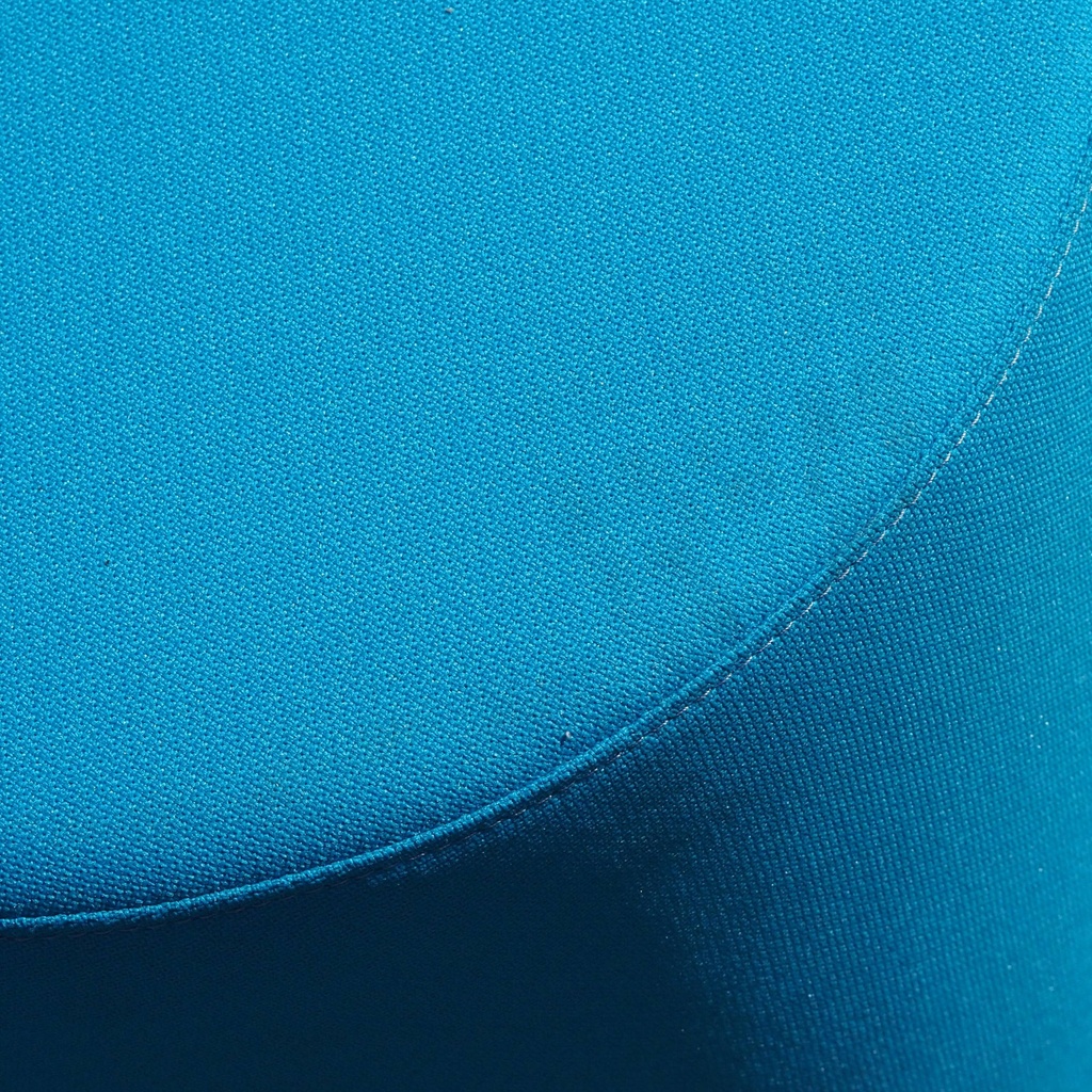 Round ottoman upholstered in various colorful fabric